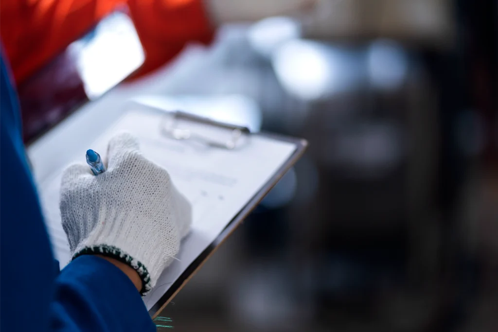 Inspector wearing gloves writes notes on a clipboard during a Section 8 inspection to document housing conditions.